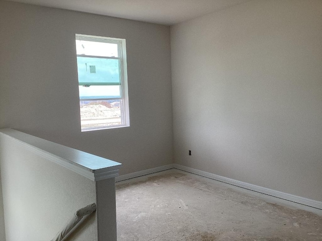 empty room with baseboards, concrete floors, and a healthy amount of sunlight