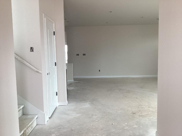 hallway featuring concrete floors and stairway