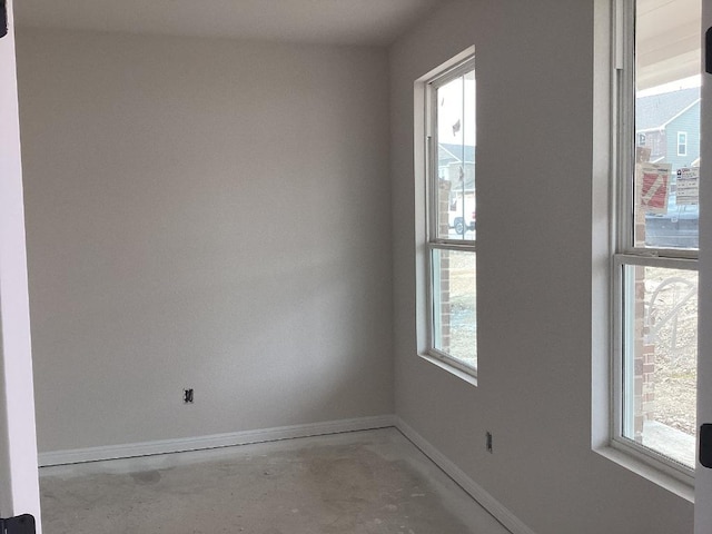 unfurnished room featuring baseboards and unfinished concrete flooring