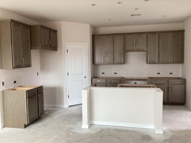 kitchen with concrete flooring, baseboards, and a center island