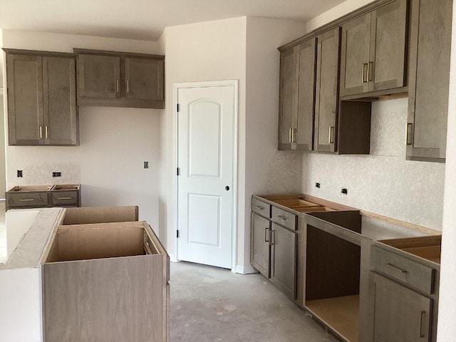 kitchen with dark brown cabinetry and concrete flooring