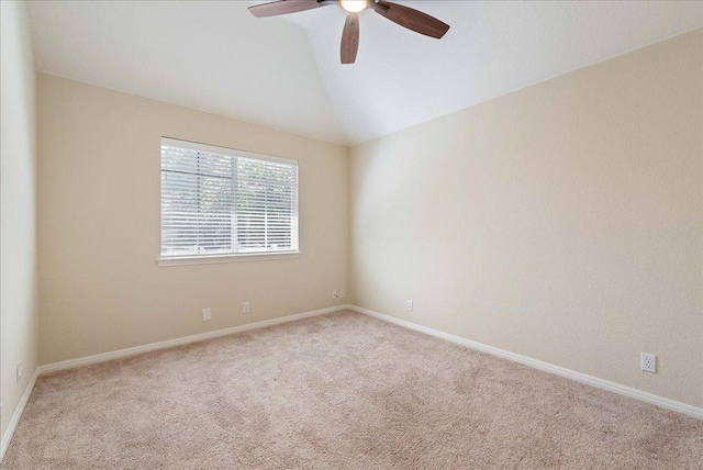 carpeted spare room featuring a ceiling fan, vaulted ceiling, and baseboards