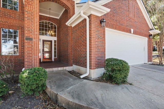 doorway to property with concrete driveway, brick siding, and an attached garage