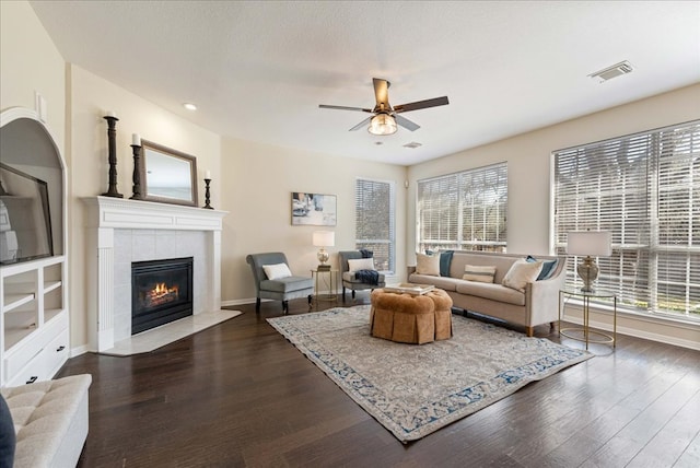 living area featuring plenty of natural light, visible vents, dark wood finished floors, and a tile fireplace