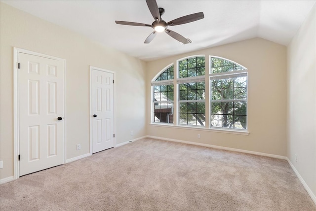 carpeted spare room featuring ceiling fan, baseboards, and vaulted ceiling