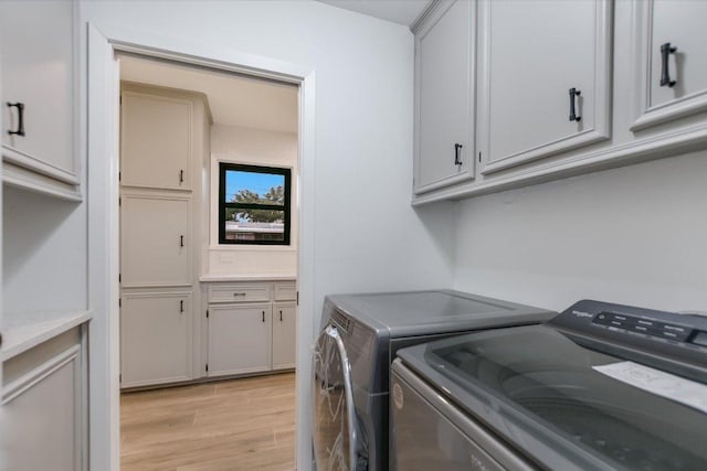 laundry area with cabinet space, washer and clothes dryer, and light wood finished floors