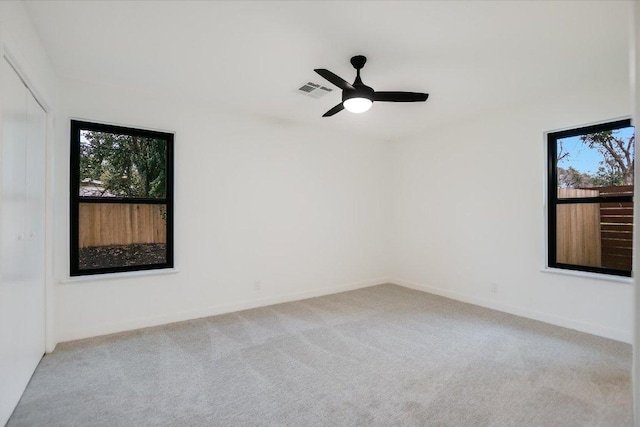 carpeted empty room featuring baseboards, visible vents, and ceiling fan