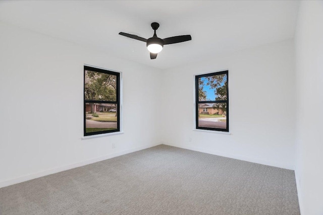 carpeted spare room with ceiling fan and baseboards