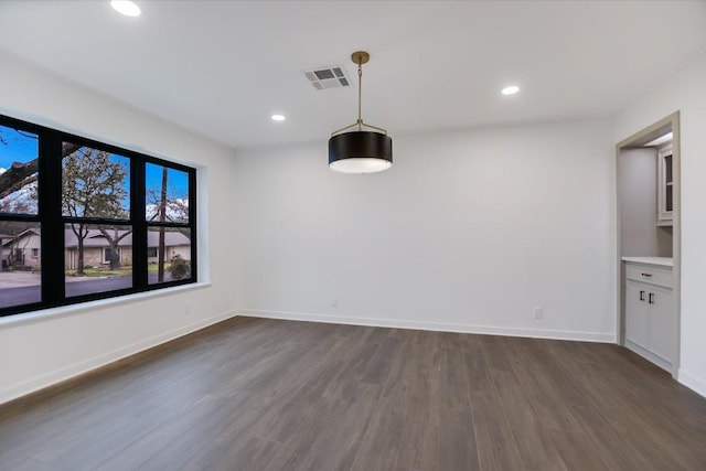 unfurnished dining area featuring dark wood-type flooring, recessed lighting, visible vents, and baseboards