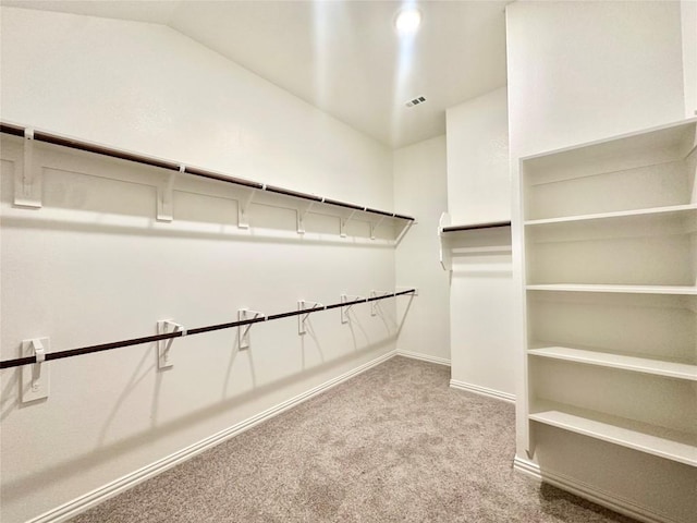 walk in closet featuring carpet flooring, visible vents, and lofted ceiling