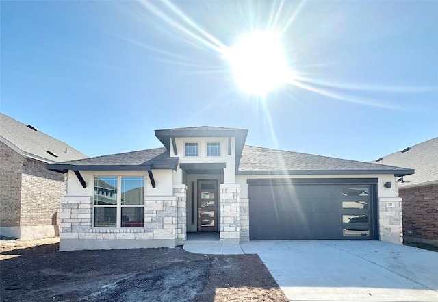 prairie-style house with stone siding, stucco siding, driveway, and a garage