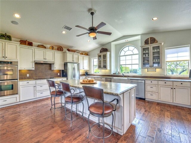 115 Hill Loop, Spicewood, TX 78669 - kitchen featuring stainless steel appliances, vaulted ceiling, dark wood-type flooring, a kitchen island, and visible vents