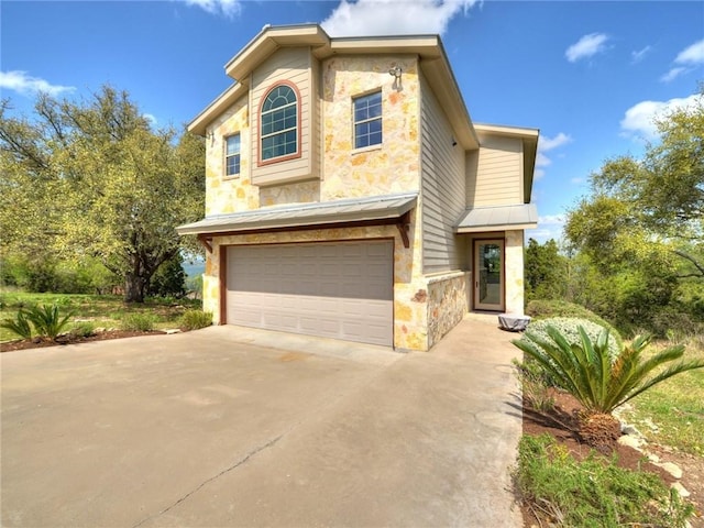 traditional home with driveway, a garage, stone siding, metal roof, and a standing seam roof