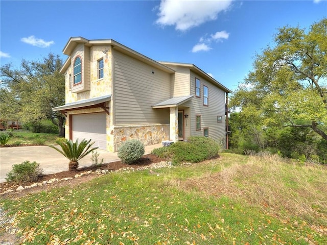 view of front of home featuring an attached garage, concrete driveway, and stone siding