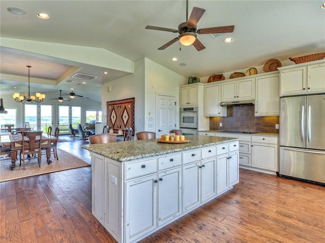 kitchen featuring black electric cooktop, vaulted ceiling, hardwood / wood-style floors, and stainless steel refrigerator