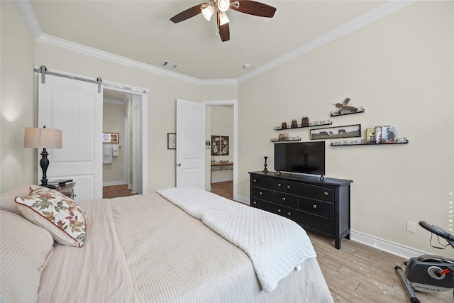 bedroom featuring crown molding, visible vents, a barn door, wood finished floors, and baseboards