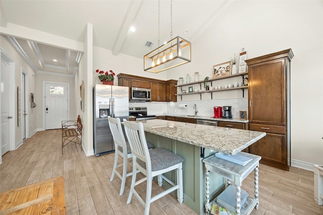 kitchen with light wood-style flooring, stainless steel appliances, a sink, a kitchen island, and open shelves