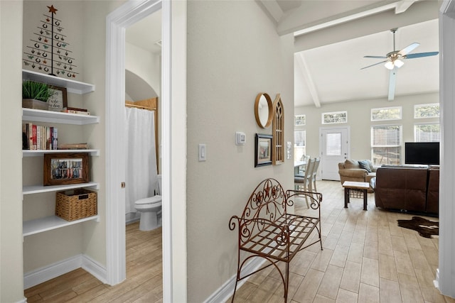 hallway featuring wood tiled floor, lofted ceiling with beams, and baseboards