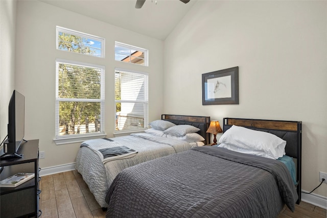 bedroom featuring ceiling fan, high vaulted ceiling, wood finished floors, and baseboards