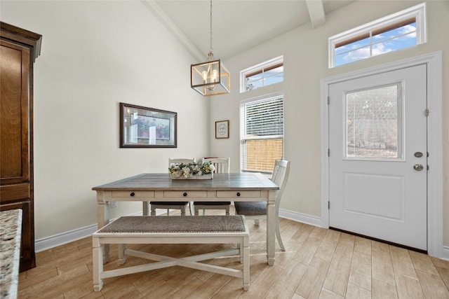 dining space with light wood-style floors, baseboards, and high vaulted ceiling