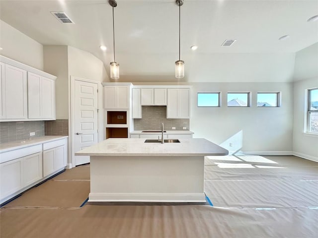 kitchen featuring visible vents, white cabinets, lofted ceiling, and a sink