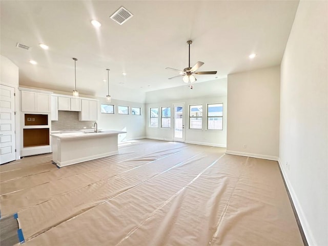 unfurnished living room with a sink, visible vents, baseboards, and recessed lighting