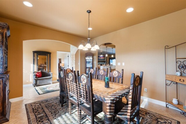 dining room featuring arched walkways, a notable chandelier, recessed lighting, and light tile patterned floors