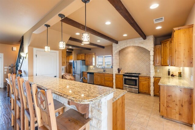 kitchen featuring stainless steel appliances, a breakfast bar, a sink, backsplash, and beam ceiling