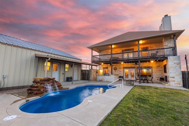 pool at dusk with fence, a yard, french doors, an outdoor pool, and a patio area