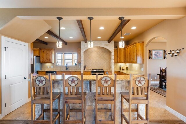 kitchen with stainless steel appliances, arched walkways, a sink, and tasteful backsplash