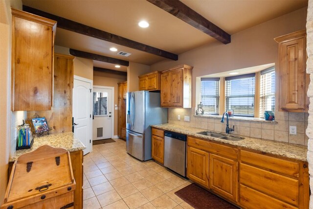 kitchen with appliances with stainless steel finishes, decorative backsplash, a sink, and beamed ceiling