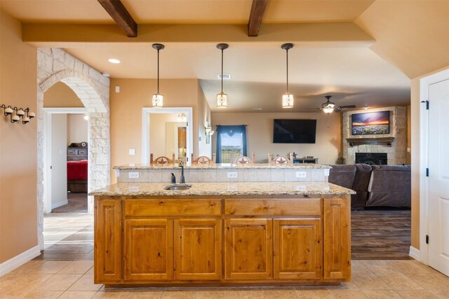 kitchen with arched walkways, light tile patterned flooring, a fireplace, and beam ceiling