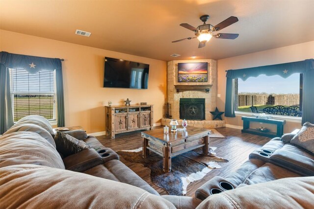 living room featuring visible vents, a fireplace, baseboards, and wood finished floors