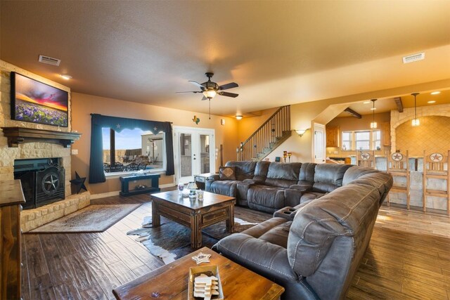 living area with stairs, visible vents, a fireplace, and wood finished floors