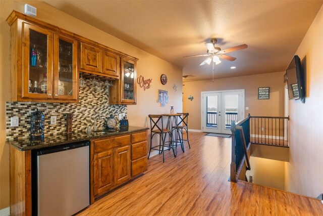 kitchen featuring french doors, backsplash, brown cabinetry, light wood-type flooring, and dishwashing machine