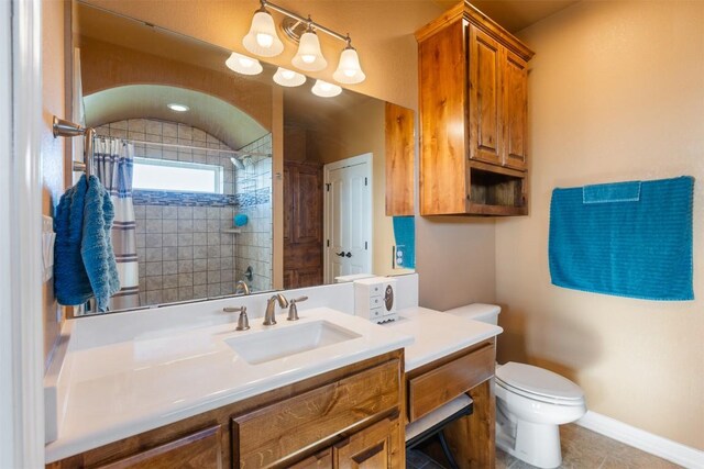 full bathroom with baseboards, tiled shower, vanity, and toilet