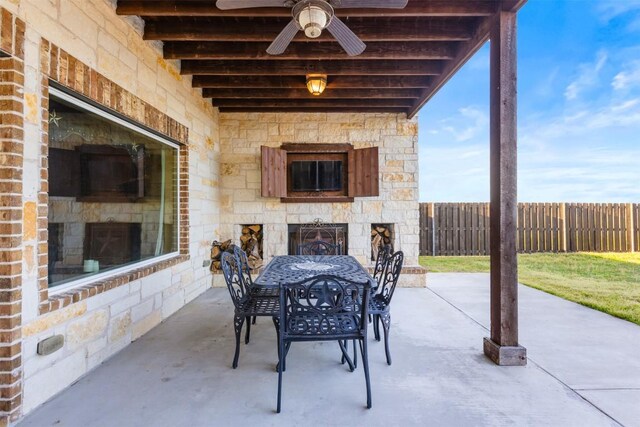 view of patio featuring ceiling fan, fence, an outdoor stone fireplace, and outdoor dining space