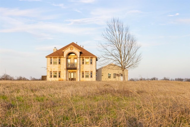 view of front of house featuring a chimney and a balcony