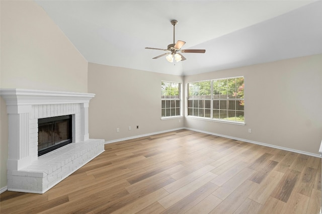 unfurnished living room with a brick fireplace, light wood-style flooring, baseboards, and a ceiling fan