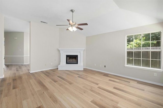 unfurnished living room with lofted ceiling, a brick fireplace, light wood-style flooring, and visible vents