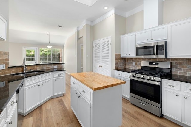 kitchen with appliances with stainless steel finishes, butcher block counters, a sink, and tasteful backsplash