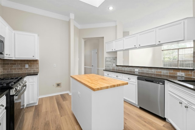 kitchen featuring butcher block countertops, white cabinetry, light wood-type flooring, dishwasher, and gas range