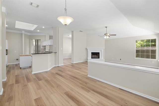 unfurnished living room with a fireplace with raised hearth, recessed lighting, a ceiling fan, visible vents, and light wood-style floors