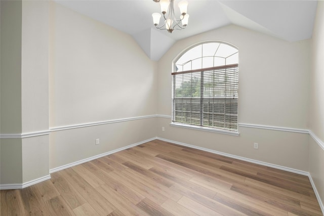 empty room with lofted ceiling, an inviting chandelier, baseboards, and wood finished floors