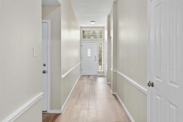 doorway to outside featuring light wood-style flooring and baseboards