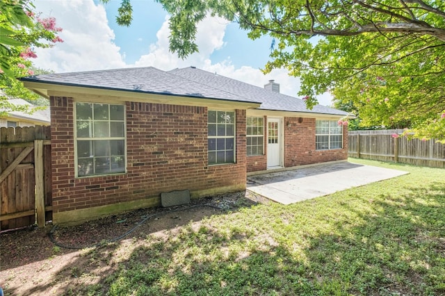 rear view of house featuring brick siding, a yard, a chimney, a patio area, and a fenced backyard