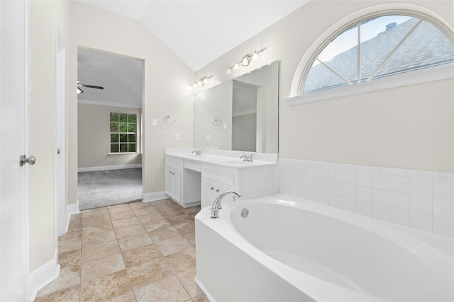 full bath with double vanity, vaulted ceiling, baseboards, and a bath