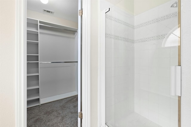 full bathroom featuring visible vents, a spacious closet, and tiled shower