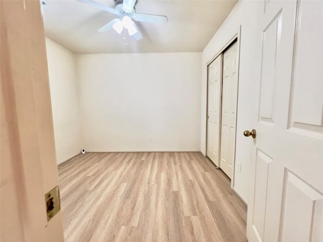 unfurnished bedroom featuring light wood finished floors, baseboards, a ceiling fan, and a closet