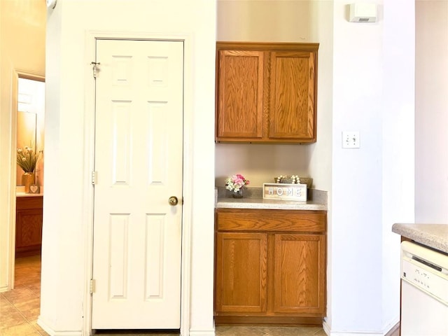 kitchen with light countertops, brown cabinetry, and white dishwasher